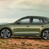 Grüner Audi Q5 mit 3,0 l V6 Diesel-Motorisierung steht auf einem felsigen Untergrund vor einem modernen Gebäude.