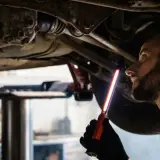 Mechaniker prüft das Fahrwerk eines Autos, um sicherzustellen, dass das audi s tronic Getriebe einwandfrei funktioniert.