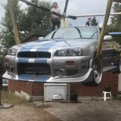 Der ikonische Paul Walker Nissan Skyline R34, bekannt aus "Fast & Furious", wird von einem Kran angehoben.