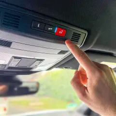 Finger drückt SOS-Knopf im Auto. In welcher Situation eCall auslöst, ist hier nicht ersichtlich, aber es ist ein Notruf.