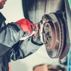 Mechaniker mit roten Handschuhen repariert eine festsitzende Bremse. Was tun? Werkstattarbeit.