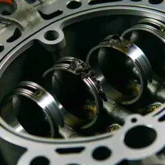 Nahaufnahme eines Motors mit sichtbaren Kolbenringen. Ablagerungen deuten auf defekte Kolbenringe Symptome hin.