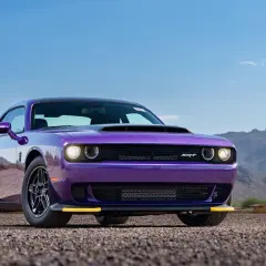 Lila Dodge Demon 170 mit gelben Akzenten steht auf Schotter vor einer Bergkulisse.