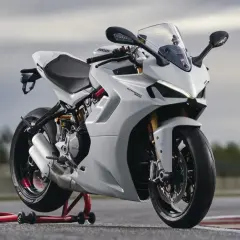 Eine weiße Ducati Supersport 950 steht auf einem roten Motorradständer. Das Motorrad hat einen sportlichen Look mit scharfen Linien und einem aerodynamischen Design.