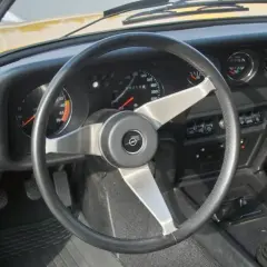 Der opel gt innenraum zeigt ein ledernes Lenkrad, klassische Rundinstrumente und einen Schaltknüppel.