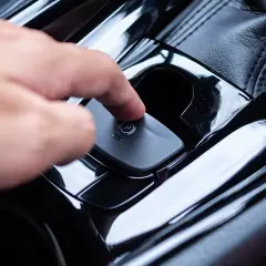 Ein Finger drückt auf den Knopf der elektronischen Handbremse. So funktioniert eine Handbremse im modernen Auto.