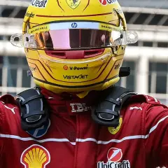 Sir Lewis Hamilton feiert in seinem gelben Ferrari-Helm und rotem Rennanzug einen Sieg.