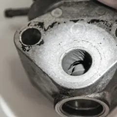 Detailaufnahme eines metallischen Bauteils, vermutlich ein p0402 vw Teil, mit sichtbaren Bohrungen und Gebrauchsspuren.