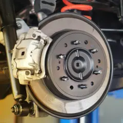 Nahaufnahme einer Autobremsanlage. Die Bremsbeläge greifen die neue Bremsscheibe. Zeit, die Bremsscheiben zu wechseln.