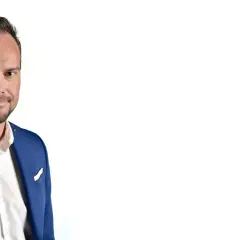 Markus Flasch, ein Mann mit Bart und blauem Anzug, lächelt in die Kamera.