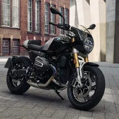 Schwarze BMW R 12 mit Café Racer Verkleidung steht auf Kopfsteinpflaster vor einer Backsteinfassade.