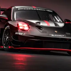 Porsche 992 GT3 R Rennwagen in Schwarz mit roten Akzenten und leuchtenden Scheinwerfern.