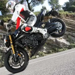 Motorradfahrer im Stunt, das Vorderrad in der Luft. Der Bremsweg des Motorrads ist hier irrelevant, da er gerade einen Wheelie macht.