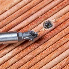 Ein Schraubenextraktor mit Metallspänen auf Holzoberfläche.