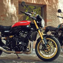 Zwei Kawasaki Z900RS, ein retro Motorrad in Schwarz-Rot, und ein weiteres in Schwarz, stehen vor einer Ziegelwand.