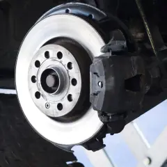 Nahaufnahme einer Bremsscheibe aus Metall, die an einem Auto montiert ist. Das Material der Bremsscheibe ist robust und für hohe Temperaturen ausgelegt.