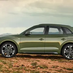 Grüner Audi Q5 mit 3,0 l V6 Diesel-Motorisierung steht auf einem felsigen Untergrund vor einem modernen Gebäude.