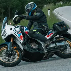 Motorradfahrer mit Helm und Ausrüstung nimmt eine Kurve, der Lenkimpuls des Motorrads ist deutlich zu sehen.