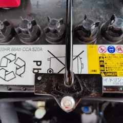 Mitsubishi Space Star Batterie wechseln: Das Bild zeigt eine Autobatterie mit Warnhinweisen und Spezifikationen wie 20HR 66Ah CCA 520A.