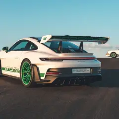 Zwei weiße Porsche 992 GT3 RS mit grünen Akzenten, einer im Vordergrund, der andere im Hintergrund, der an den Carrera RS erinnert.
