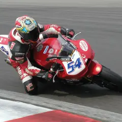 Rennfahrer Kenan Sofuoğlu in roter Lederkombi auf roter Yamaha mit Startnummer 54, in Schräglage auf der Rennstrecke.