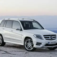 Weißer Mercedes GLK steht auf felsigem Untergrund vor bergiger Kulisse.