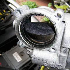 Stark verschmutztes AGR-Ventil eines Volvo XC60, bereit zum Ausbau. Rußablagerungen blockieren den Durchgang.