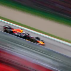 Ein Formel 1 Rennwagen rast über die Strecke, die Streifen von Rot und Grün verschwimmen. Ein Bild voller Dynamik, das die Geschwindigkeit und Aufregung des Rennsports einfängt.