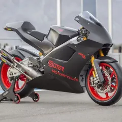 Schwarzes Suter MMX 500 Motorrad mit roten Felgen und Akrapovič Auspuffanlage auf einem Rennstreckenständer.