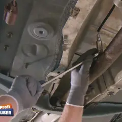 Hände mit Handschuhen wechseln die Lambdasonde an einem Ford Fiesta.