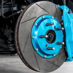 Ein leuchtend blauer Bremssattel umgibt eine geschlitzte Bremsscheibe. Die Bremsen blockieren, um die Sicherheit zu gewährleisten.
