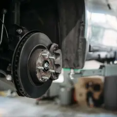 Detailaufnahme einer Autobremsanlage: Bremsscheibe, Bremssattel und Radnabe. So sieht eine Bremse aus, wenn sie für Wartungsarbeiten demontiert ist.