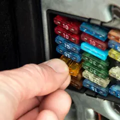 Hand prüft Sicherungen im Auto. So erkennt man eine defekte Sicherung: Der Draht im Inneren ist durchgebrannt.