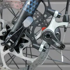 Nahaufnahme einer Fahrradbremse mit verschiedenen Arten von Bremsscheiben und einem TRP Spyre-Bremssattel.