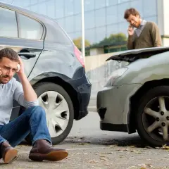Mann sitzt nach Autounfall am Boden, ruft Hilfe. Der andere Fahrer spricht am Handy. Offenbar hat das **Auto bremst nicht mehr**.