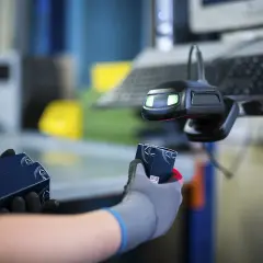 Hände mit Handschuhen halten Topran-Verpackungen unter einem Scanner. Gute Topran Erfahrungen im Lager.