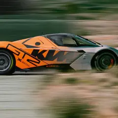 Orange-grauer KTM GT2-Sportwagen rast über die Rennstrecke, mit verschwommenem Hintergrund.