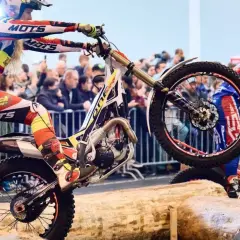 Motorrad-Fahrer in Aktion bei einem Hindernisparcours mit Holzstämmen.