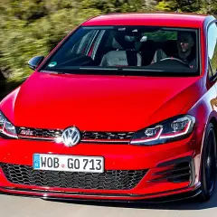 Roter Golf 7 GTI im Test auf einer kurvigen Straße, Fahrer im Inneren.
