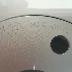 Nahaufnahme einer Bremsscheibe mit eingravierter Kennzeichnung "E1 90 R-02 C0120".
