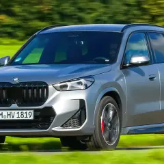 Grauer BMW X1 xDrive23d fährt auf einer grünen Wiese. Keine Probleme sichtbar, nur Fahrspaß.