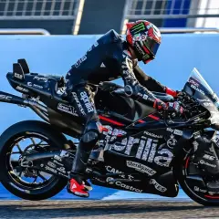 Marco Bezzecchi in voller Fahrt bei einem MotoGP-Rennen. Sein schwarzer Anzug und das Motorrad sind mit Sponsorenlogos bedeckt.