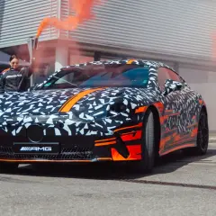 Tarnkappen-AMG GT4 mit orangem Rauch und Rennfahrern.