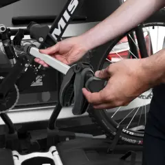 Hände montieren Fahrrad am Thule EasyFold XT 2. Ein Griff klemmt, was auf Thule EasyFold XT 2 Probleme hindeuten könnte.