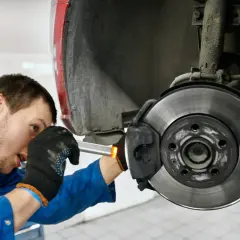 Mechaniker prüft die **bremse auto links oder rechts**. Er arbeitet am Bremssattel und der Bremsscheibe.