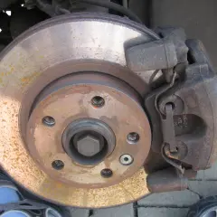 Bremsbeläge und Bremsscheibe zeigen Rostspuren. Das Auto klackert beim Bremsen, was auf Verschleiß hindeutet.