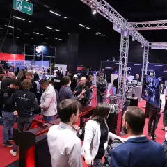 Besucher auf der Professional Motorsport World Expo, die sich über Rennsporttechnologie informieren.
