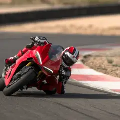 Ein Rennfahrer auf einer roten Ducati Panigale V2 lehnt sich tief in eine Kurve auf einer Rennstrecke.