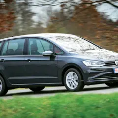 Dunkelgrauer VW Golf Sportsvan fährt auf einer Landstraße. Probleme mit dem Auto sind nicht ersichtlich.