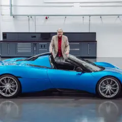 Gordon Murray präsentiert stolz seinen neuen Gordon Murray T.33, einen leuchtend blauen Supersportwagen in einer Werkstatt.